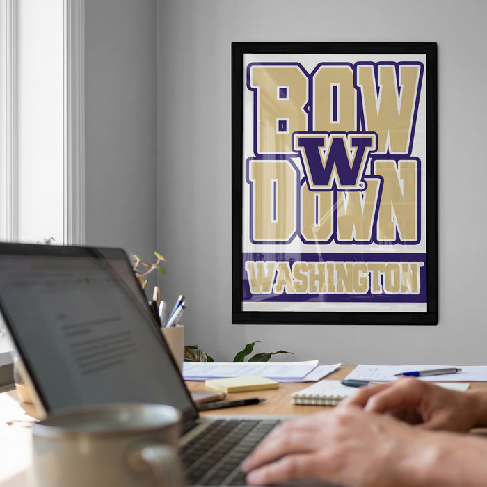 a person working on a laptop at a desk, with a framed poster of the Washington University team on the wall behind them.