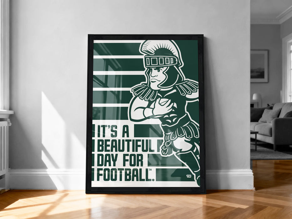 A framed poster featuring a cartoon character in a green and white color scheme, with the text "It's a beautiful day for football!" displayed prominently.