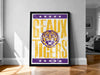 A framed poster with the text "GEAUX TIGERS" and a tiger graphic, placed on a wooden floor against a white wall.