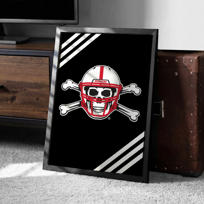 A framed poster with a skull and crossbones design, featuring a football helmet, is displayed on a carpeted floor next to a wooden chest.