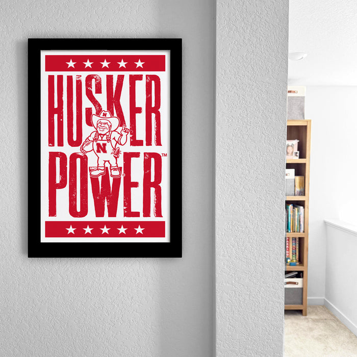 a framed poster with the text "HUSKER POWER" and a graphic of a person wearing a fireman's helmet.