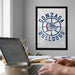 a framed poster of the Gonzaga Bulldogs on the wall, with a laptop and a coffee cup on a desk in the foreground.
