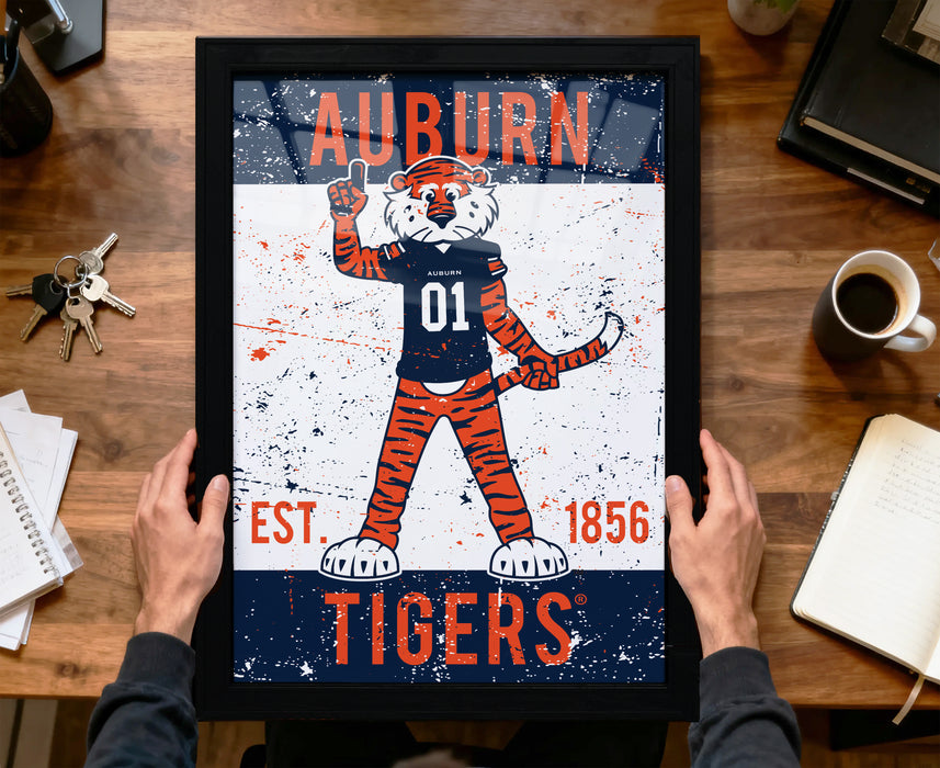 A framed poster featuring an illustration of a tiger character with the text "AUBURN TIGERS" and "EST. 1856" printed on it.