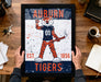 A framed poster featuring an illustration of a tiger character with the text "AUBURN TIGERS" and "EST. 1856" printed on it.