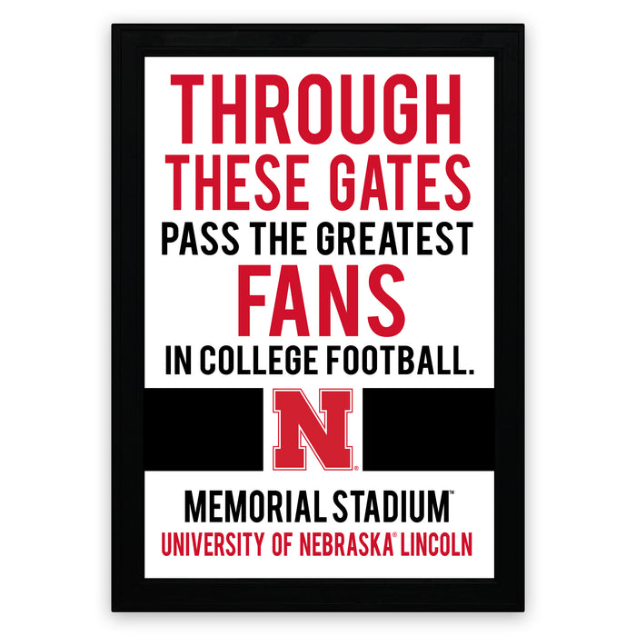 The image is a framed poster with text that reads "THROUGH THESE GATES PASS THE GREATEST FANS IN COLLEGE FOOTBALL. N MEMORIAL STADIUM UNIVERSITY OF NEBRASKA LINCOLN".