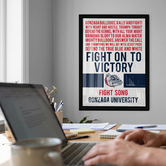 a framed poster with a motivational message about fighting for victory, displayed on a wall in a room with a desk and laptop in the foreground.