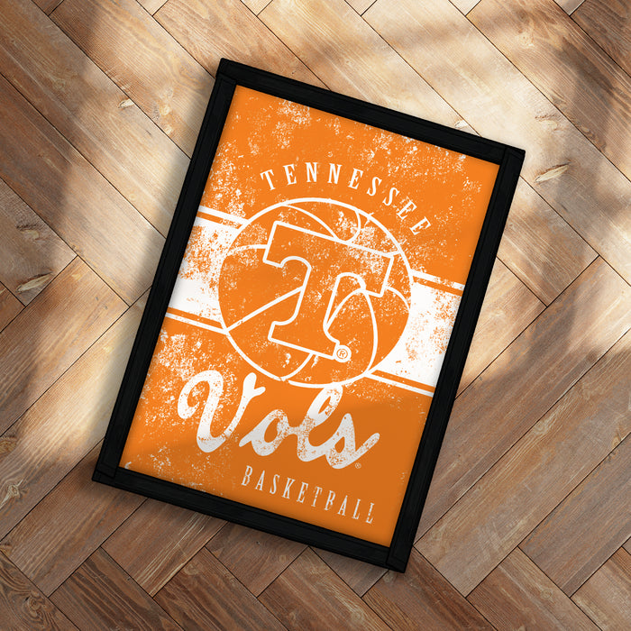 A framed poster with the text "TENNESSEE Vols" and a basketball graphic, placed on a wooden floor.