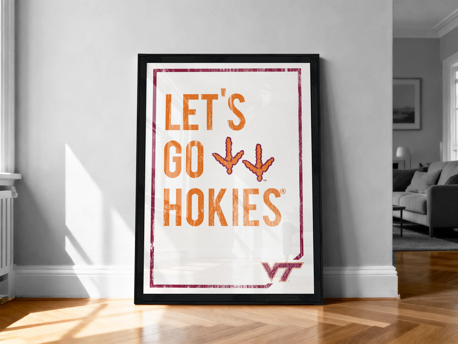 A framed poster with the text "LET'S GO HOKIES" and a graphic of a bird's feet, placed on a wooden floor against a white wall.