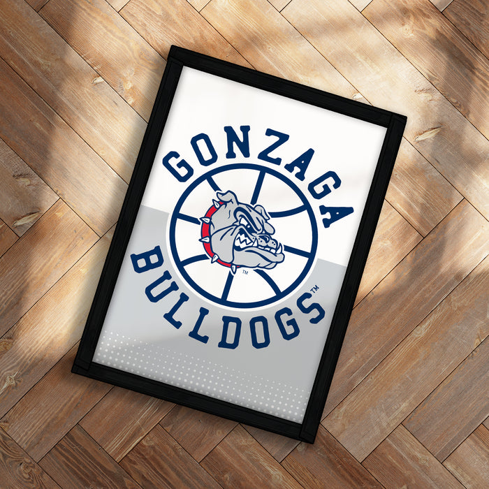 A framed poster with the Gonzaga Bulldogs logo on it, placed on a wooden floor.