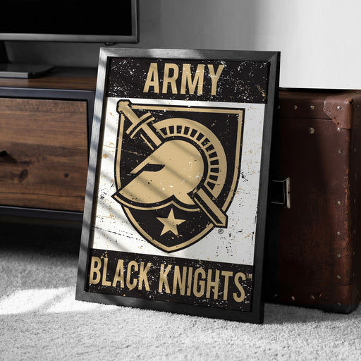 A framed poster with the text "ARMY BLACK KNIGHTS" and a graphic of a helmet and sword, placed on a carpeted floor next to a wooden chest.