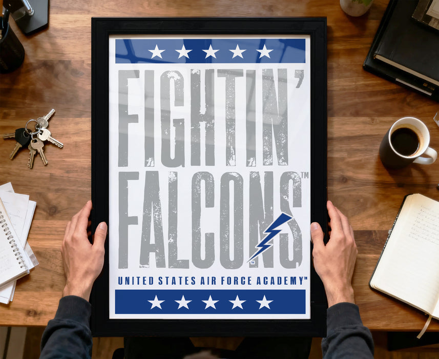 A framed poster with the text "FIGHTIN' FALCONS" and the logo of the United States Air Force Academy is being held by a person's hands.