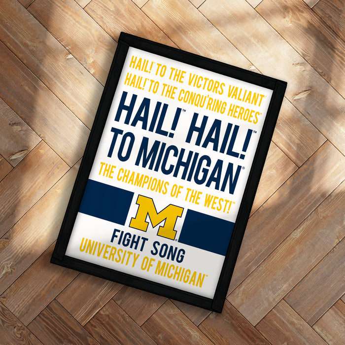 The image is a framed poster with text that reads "Hail! to the victors' valiant hail! to the conquering heroes hail! to the champions of the west! fight song university of michigan".