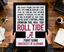 a framed poster with text that reads "For Bama's Pluck and Grit Have WRIT HER NAME IN CRIMSON FLAME FIGHT ON, FIGHT ON, FIGHT ON MEN! REMEMBER THE ROSE BOWL, WE'LL WIN THEN GO, ROLL TO VICTORY, HIT YOUR STRIDE, YOU'RE DIXIE'S FOOTBALL PRIDE CRIMSON TIDE, ROLL TIDE". The poster is being held by a person's hands, and there is a notebook, a cup, and a keychain on the desk in the background.