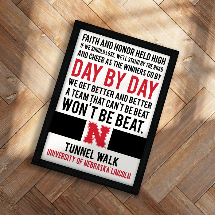 a framed motivational quote from the University of Nebraska Lincoln, which reads: "Faith and honor held high if we should lose, we'll stand by the road and cheer as the winners go by. Day by day, we get better and better a team that can't be beat. Won't be beat."