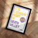 A framed poster with text and a tiger logo, placed on a wooden floor.