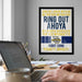 a framed poster with text on it, hanging on a wall above a desk with a laptop and other items on it.