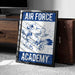 a framed poster with the text "AIR FORCE ACADEMY" and an illustration of a bird, likely representing the Air Force Academy.
