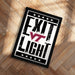 A framed poster with the text "EXIT LIGHT" and a logo, placed on a wooden floor.