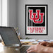 a person working on a laptop computer, with a framed poster of the University of Utah logo hanging on the wall behind them.