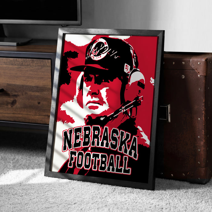 A framed poster of a man wearing a Nebraska football hat, with the text "NEBRASKA FOOTBALL" prominently displayed.