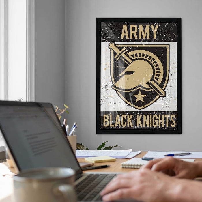 a poster of the Army Black Knights on the wall, with a laptop and a coffee cup on a desk in the foreground.