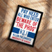 A framed poster with the text "PAY HEED ALL WHO ENTER BEWARE OF THE PHOG" and the university's logo, placed on a wooden floor.