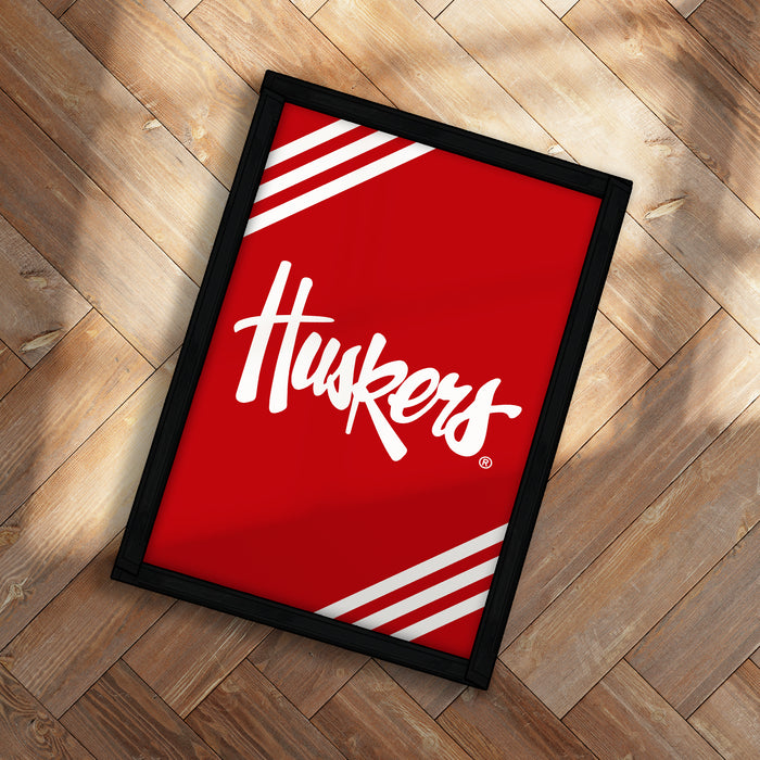A framed poster with the word "Huskies" written on it, placed on a wooden floor.