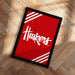 A framed poster with the word "Huskies" written on it, placed on a wooden floor.