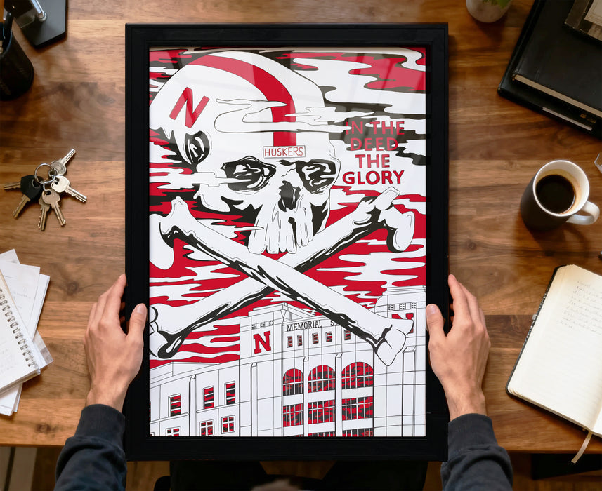 A framed poster featuring a skull and crossbones design with the text "In the Deed the Glory" and "N Huskers" printed on it, along with a building labeled "NU".