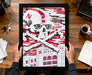 A framed poster featuring a skull and crossbones design with the text "In the Deed the Glory" and "N Huskers" printed on it, along with a building labeled "NU".