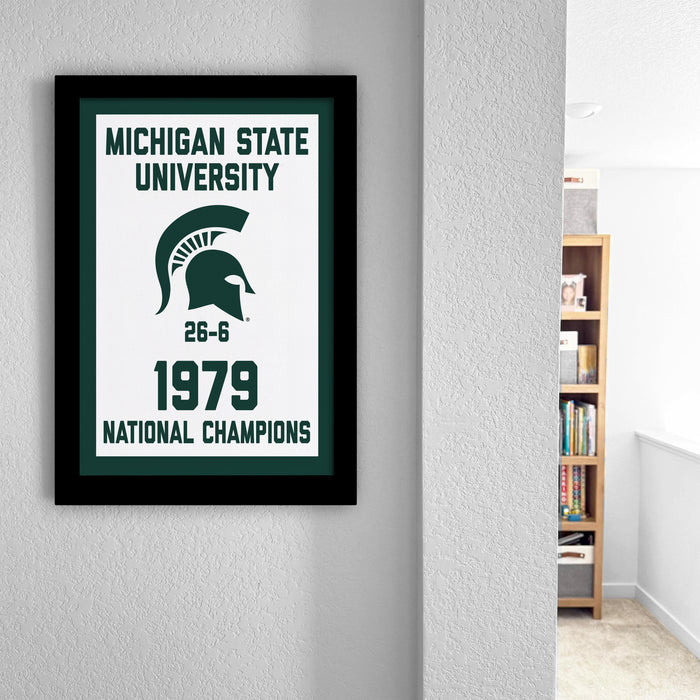 A framed poster on a wall celebrating the Michigan State University's 1979 National Champions, featuring the university's logo and the text "Michigan State University 1979 NATIONAL CHAMPIONS".