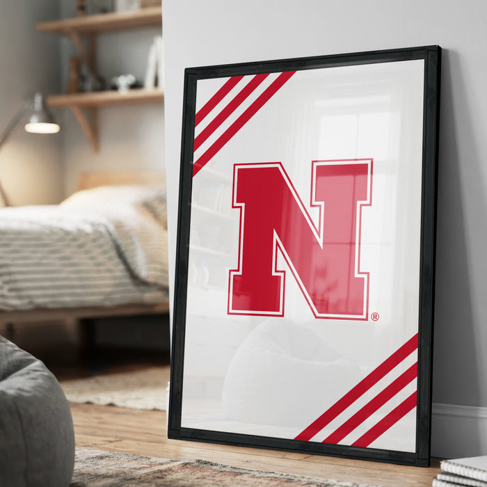 A framed poster with a large red letter "N" on a white background, placed on a wall in a room.