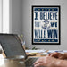 a framed poster with the text "I BELIEVE THAT WE WILL WIN" on it, which is displayed on a wall above a desk with a laptop and other items.