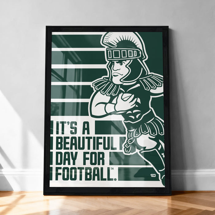 A framed poster featuring a cartoon character in a football uniform, with the text "It's a beautiful day for football" displayed below the image.