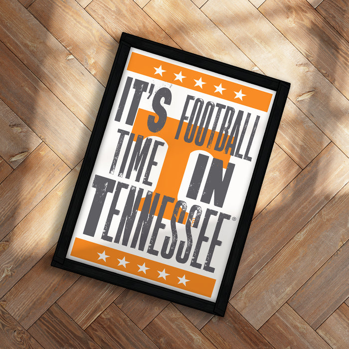 A framed poster with the text "IT'S FOOTBALL TIME IN TENNESSEE" printed on it, placed on a wooden floor.