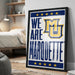 A framed poster with the text "WE ARE MARQUETTE" and a logo, placed on a wall in a bedroom.