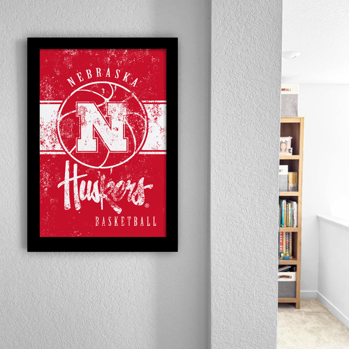 a framed poster of the Nebraska Huskies basketball team, with the team's logo and text prominently displayed.