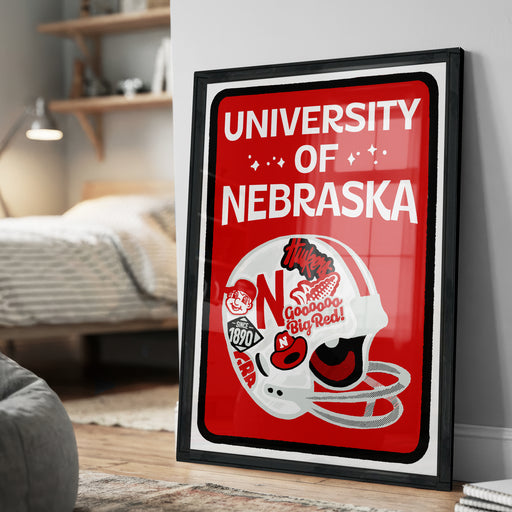 A framed poster of a football helmet with the text "UNIVERSITY OF NEBRASKA" and various football-related graphics and text.