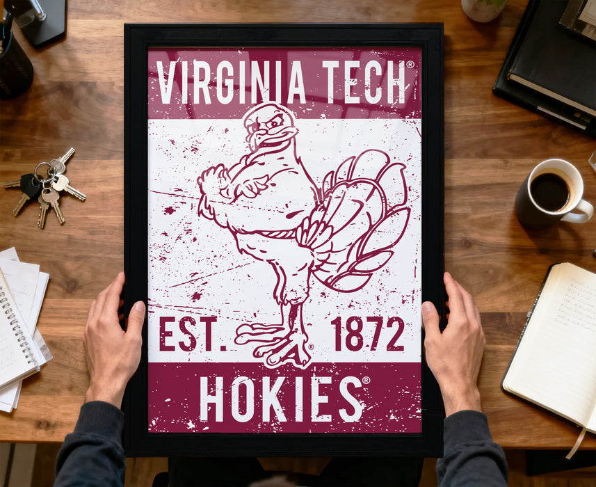 A framed poster featuring a turkey and the text "VIRGINIA TECH EST. 1872 HOKIES" is being held by a person's hands.