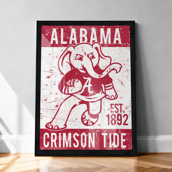 a framed poster with a red and white design depicting a cartoon elephant holding a football. The poster has the text "ALABAMA" and "CRIMSON TIDE" printed on it.