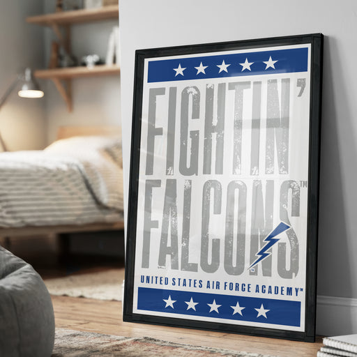 a framed poster with the text "FIGHTIN' FALCONS" and "United States Air Force Academy" on it, placed on a wall in a bedroom setting.