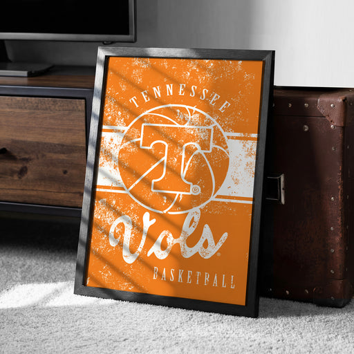 a framed poster with the text "TENNESSEE VIRS BASKETBALL" on it, placed on a carpeted floor next to a wooden chest.