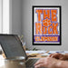 a person working on a laptop at a desk, with a framed poster of the University of Alabama's Tigers logo hanging on the wall behind them.