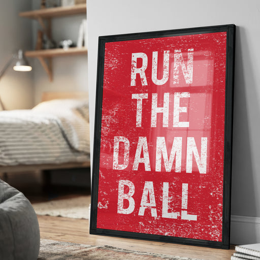 A framed poster with the text "RUN THE DAMN BALL" in white letters against a red background.