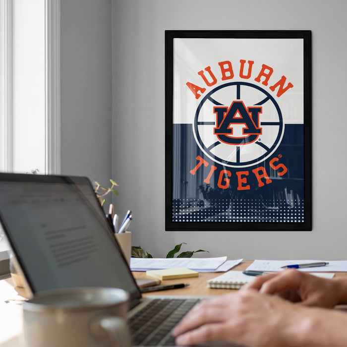 a framed poster of the Auburn Tigers, a sports team, on a wall in a room with a desk and a laptop.