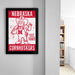 a framed poster of a Cornhuskers mascot, a character from the University of Nebraska at Omaha, with the text "NEBRASKA CORNHUSKERS EST. 1869".
