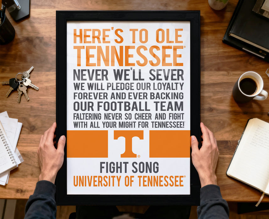A person is holding up a framed poster with the text "HERE'S TO OLE TENNESSEE" and "FIGHT SONG UNIVERSITY OF TENNESSEE" printed on it.