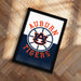 A framed poster with the text "AUBURN TIGERS" and a basketball logo, placed on a wooden floor.