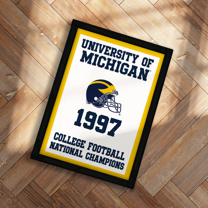 A framed poster with the text "UNIVERSITY OF MICHIGAN 1997 COLLEGE FOOTBALL NATIONAL CHAMPIONS" and a football helmet graphic.