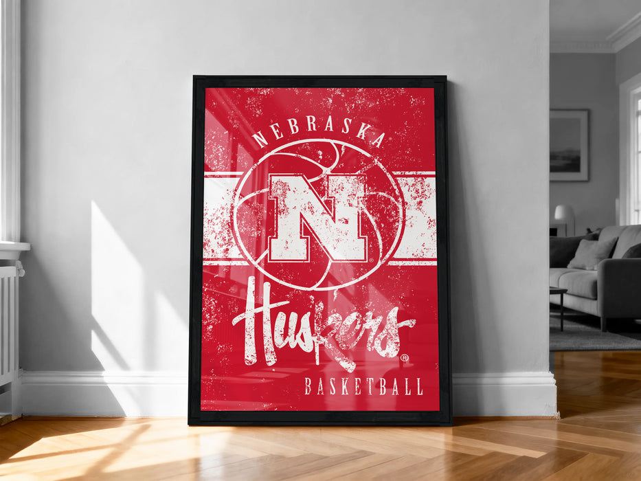 A framed poster of the Nebraska Huskies basketball team, featuring the team's logo and text, is displayed on a wall in a room.